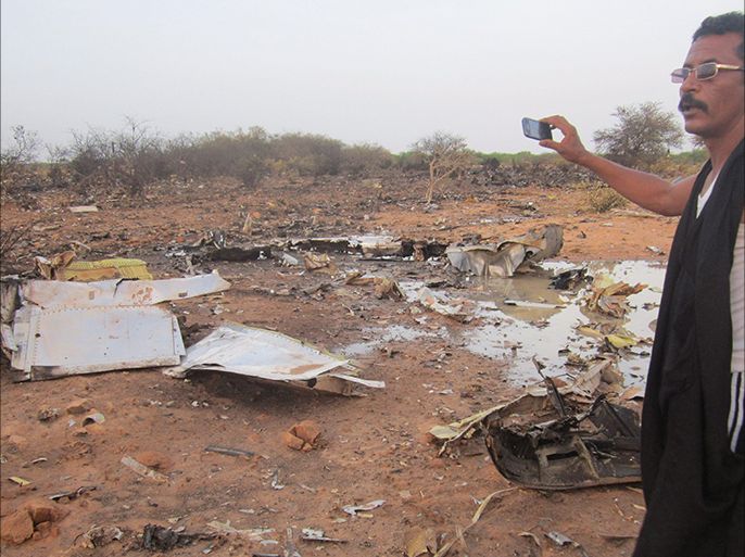 A man takes a picture of the crash site of the Air Algerie flight AH5017 near the northern Mali town of Gossi, July 24, 2014. Poor weather was the most likely cause of the crash of an Air Algerie flight in the West African state of Mali that killed all 118 people on board, French officials said on Friday. Picture taken July 24, 2014. REUTERS/Stringer (MALI - Tags: DISASTER TRANSPORT TPX IMAGES OF THE DAY)