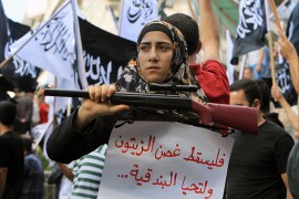 A Palestinian protester holds a placard and a fake weapon during a demonstration to support the resistance in Gaza and to protest against the Israeli military offensive on the Palestinian Gaza Strip on July 20, 2014 in the West Bank city of Ramallah. More than 60 Palestinians were killed on July 20, 2014 as Israeli forces pounded northern Gaza, sending thousands more fleeing in terror in the deadliest assault on the enclave in five years. The placard in Arabic calls for the "olive branch to fall down" and reads "long life to guns". AFP PHOTO / ABBAS MOMANI