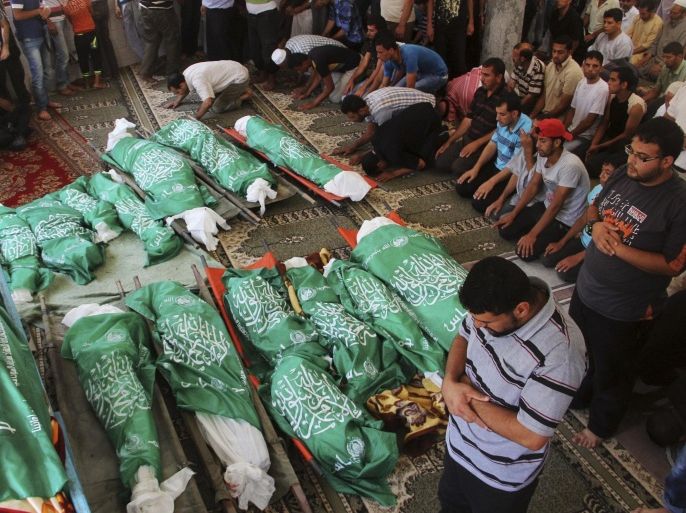 Palestinians pray over Hamas green flag-draped bodies of 17 members of the Abu Jamea immediate and extended family, killed by an Israeli strike at their house, during their funeral at the main mosque in Khan Younis, in the southern Gaza Strip, Monday, July 21, 2014. The top Hamas leader in the Gaza Strip signaled Monday that the Islamic militant group will not agree to an unconditional cease-fire with Israel, while Israel's defense minister pledged to keep fighting "as long as necessary," raising new doubt about the highest-level mediation mission in two weeks. (AP Photo/Hatem Ali)