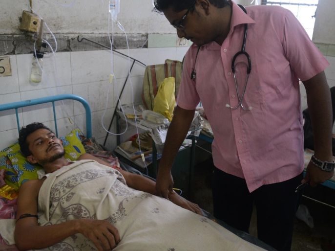 Indian patient Kamal Roy (L) is examined by a doctor while being treated for Japanese encephalitis at the North Bengal Medical College Hospital on the outskirts of Siliguri on July 22, 2014. An outbreak of encephalitis has killed 60 people in the eastern Indian state of West Bengal, a top health official has said, calling the situation 'alarming'. AFP PHOTO/ Diptendu DUTTA