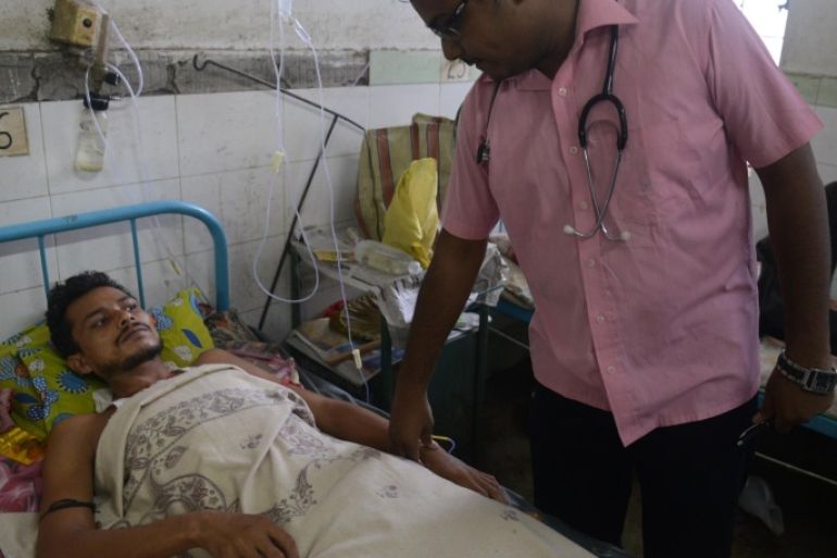 Indian patient Kamal Roy (L) is examined by a doctor while being treated for Japanese encephalitis at the North Bengal Medical College Hospital on the outskirts of Siliguri on July 22, 2014. An outbreak of encephalitis has killed 60 people in the eastern Indian state of West Bengal, a top health official has said, calling the situation 'alarming'. AFP PHOTO/ Diptendu DUTTA