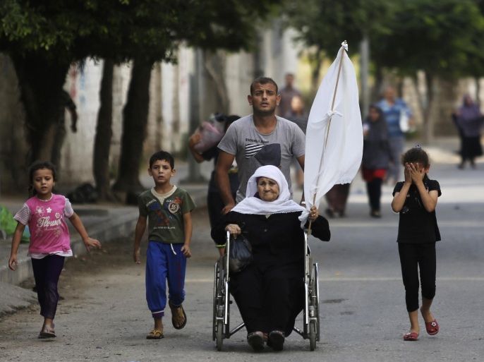 A Palestinian wheels an elderly woman as they flee their homes in the Gaza's Shijaiyah neighborhood, northern Gaza Strip, Sunday, July 20, 2014. A Gaza City neighborhood came under heavy tank fire Sunday as Israel widened its ground offensive against Hamas, causing hundreds of panicked residents to flee, including a woman in a wheelchair waving a white flag. (AP Photo/Hatem Moussa)