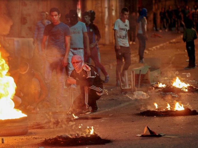 A photograph made available on 07 July 2014 showing masked Palestinian protesters from the West bank city of Hebron, during clashes with Israeli soldiers (unseen) on 06 July 2014 as they search for the kidnappers of the three Israeli teenagers who were found dead near Hebron on 30 June 2014.