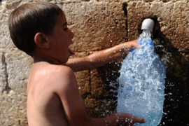 A boy fills a bottel with water in his village near the Turkish city of Reyhanli, on September 1, 2013.