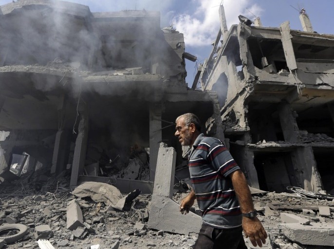 A Palestinian man walks by buildings heavily damaged by Israeli strikes in Beit Hanoun, northern Gaza Strip, Saturday, July 26, 2014. Thousands of Gaza residents who had fled Israel-Hamas fighting streamed back to devastated border areas during a lull Saturday, and were met by large-scale destruction: scores of homes were pulverized, wreckage blocked roads and power cables dangled in the streets. (AP Photo/Lefteris Pitarakis)