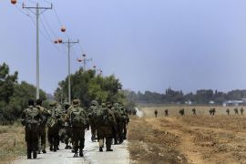 Israeli reserve soldiers return to Israel after fighting in Khan Younis in the Gaza Strip, as walking on a road near the Israel Gaza border on Wednesday, July 30, 2014. On Wednesday, Israeli aircraft struck dozens of Gaza sites, including five mosques it said were being used by militants, while several other areas came under tank fire. (AP Photo/Tsafrir Abayov)
