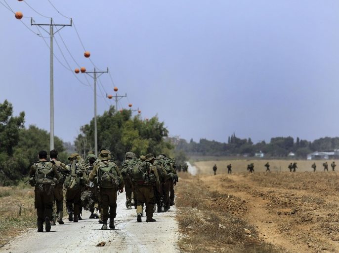Israeli reserve soldiers return to Israel after fighting in Khan Younis in the Gaza Strip, as walking on a road near the Israel Gaza border on Wednesday, July 30, 2014. On Wednesday, Israeli aircraft struck dozens of Gaza sites, including five mosques it said were being used by militants, while several other areas came under tank fire. (AP Photo/Tsafrir Abayov)