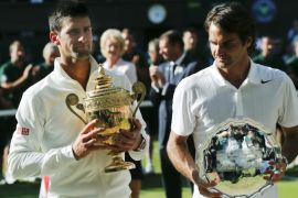Serbia's Novak Djokovic, left, holds his trophy after defeating Switzerland's Roger Federer, right, in the men's singles final match at the All England Lawn Tennis Championships in Wimbledon, London, Sunday, July 6, 2014. (AP Photo/Ben Curtis)