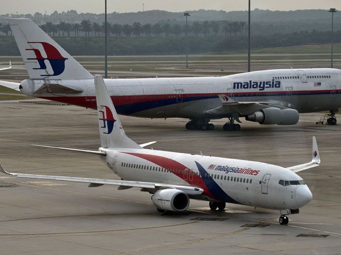 (FILES)-- A file photo taken on June 17, 2014 shows a Malaysia Airlines Boeing-737 plane taxiing past a 747 (back) from the same company at the Kuala Lumpur International Airport in Sepang. Malaysia Airlines said on July 17, 2014 that it had "lost contact" with one of its passenger planes whose last known position was over Ukraine. "Malaysia Airlines has lost contact of MH17 from Amsterdam," the airline, still reeling from the disappearance of flight MH370, said on its Twitter account. AFP PHOTO / Manan VATSYAYANA