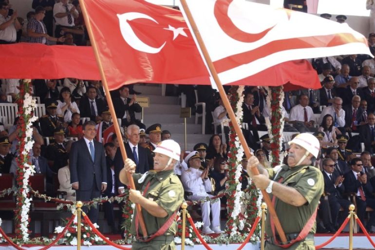 Turkish Cypriot war veterans march with Turkish and Turkish Cypriot flags, past Turkish President Abdullah Gul (back L) and Turkish Cypriot leader Dervis Eroglu, during a military parade celebrating 40 years since Turkey invaded Cyprus, in Nicosia July 20, 2014. Turkish forces landed on the island four decades ago in response to a brief Greek Cypriot coup, partitioning the island since. REUTERS/Andreas Manolis (CYPRUS - Tags: ANNIVERSARY MILITARY POLITICS)