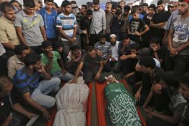 Palestinian mourners at a mosque gather around the bodies of Mousa Abu Muamer, 56, left, and his son Saddam, 27, who were killed in an overnight Israeli missile strike at their house in the outskirts of the town of Khan Younis, southern Gaza Strip, Monday, July 14, 2014. (AP Photo/Lefteris Pitarakis)