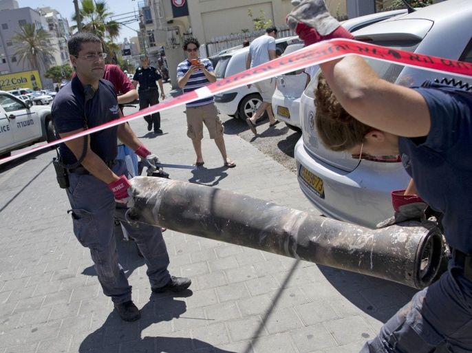 Israeli explosives experts carry the remnants of a long-range rocket fired by Palestinians militants from Gaza after being shot down by Israel’s Iron Dome air defense system and hit a synagogue in Tel Aviv, Israel, Friday, July 11, 2014. Gaza rocket fire struck a gas station and set it ablaze Friday in southern Israel, seriously wounding one person as rocket fire also came from Lebanon for the first time in the four-day offensive. (AP Photo/Oded Balilty)