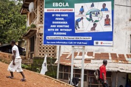 People walk past a billboard encouraging people suffering from symptoms linked to Ebola to present themselves at a health facility for treatment in Freetown, Sierra Leone, Thursday, Aug. 7, 2014. While the Ebola virus outbreak has now reached four countries, Liberia and Sierra Leone account for more than 60 percent of the deaths, according to the World Health Organization. The outbreak that emerged in March has claimed at least 932 lives. (AP Photo/ Michael Duff)
