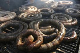A man barbecues sausages during the "Asuncion a la Parrilla" event at the former Metropolitan Seminary in Asuncion, August 10, 2014. According to the organisers, proceeds from the sale of 1,500 kg worth of beef, pork and sausages will be used by the Municipality of Asuncion to benefit flood victims of the river Paraguay. The National Emergency Secretary estimates that about 40,000 families are affected by the flooding of the country's two main rivers, the Paraguay and the Parana. REUTERS/Jorge Adorno (PARAGUAY - Tags: ENVIRONMENT FOOD SOCIETY)