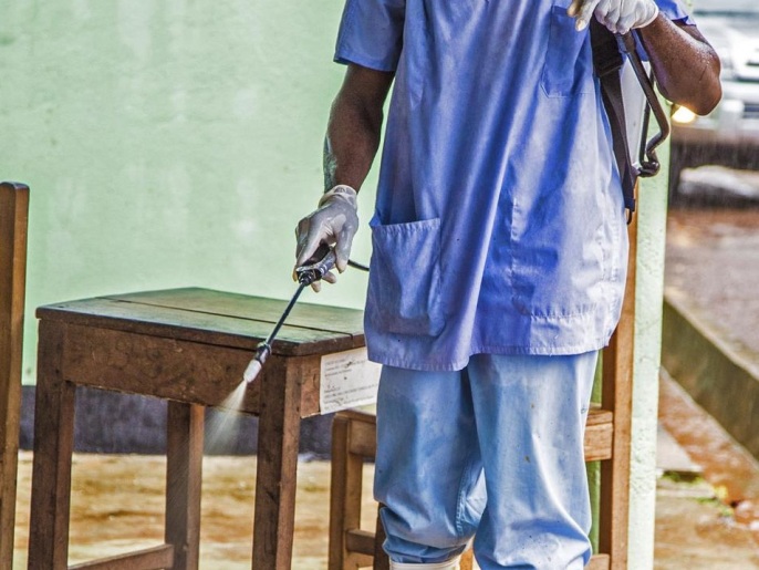 ‪موظف رعاية صحية في سيراليون يرش مادة مطهرة للقضاء على فيروس الإيبولا‬  (أسوشيتد برس)