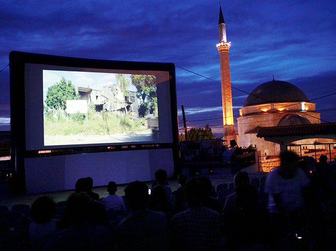 Kosovars and foreign visitors take their seats on a raised platform to watch a documentary film during Dokufest in Prizren August 20, 2014. Under a starry sky, young Kosovars take their seats alongside tourists on a platform rising from the shallow Bistrica River that cuts through Prizren, bats darting overhead in the moonlight. Others dangle their legs from the stone riverbank walls - all drawn to the latest offering of Dokufest, the 13-year-old international documentary and short film festival that is putting Kosovo well and truly on the cultural map. Picture taken August 20, 2014. REUTERS/Hazir Reka (KOSOVO - Tags: ENTERTAINMENT SOCIETY)