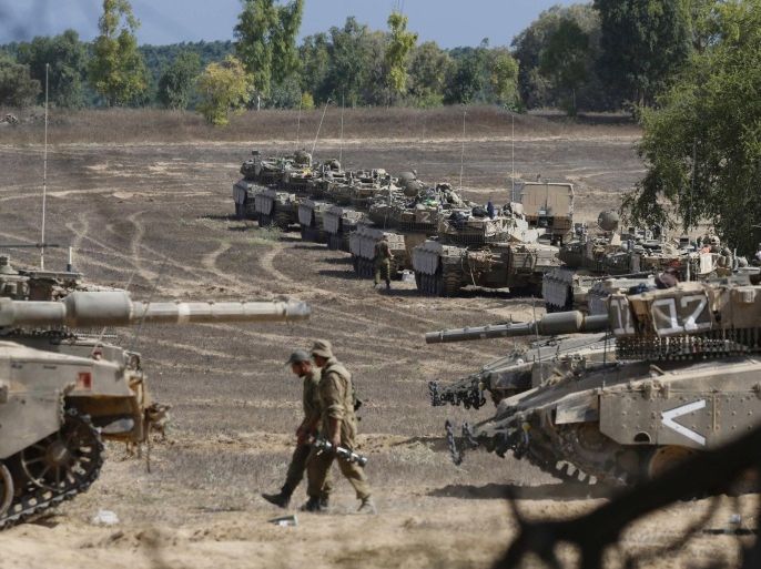 Israeli soldiers walk past tanks at a staging area near the border with Gaza Strip August 4, 2014. Palestinians accused Israel of breaking its own ceasefire on Monday by launching a bomb attack on a refugee camp in Gaza City that killed an eight-year-old girl and wounded 29 other people. Israel announced a seven-hour ceasefire to facilitate the entry of humanitarian aid and allow some of the hundreds of thousands of Palestinians displaced by an almost four-week-old war to go home. REUTERS/Nir Elias (ISRAEL - Tags: POLITICS CIVIL UNREST MILITARY CONFLICT)