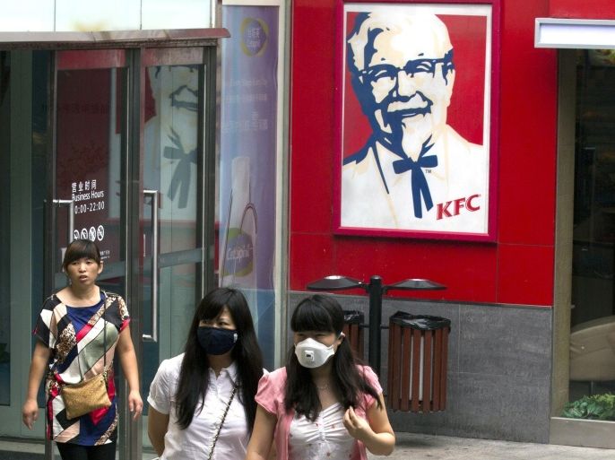 Women wearing masks during a polluted day walk outside a KFC restaurant in Beijing, China, Thursday, July 31, 2014. Already China's biggest restaurant operator with 4,600 outlets, KFC the Louisville, Kentucky-based chain is reeling after a Chinese supplier was accused of selling expired beef and chicken to it, McDonald's and possibly other restaurant chains. Just 18 months earlier, KFC's sales plunged in China after a supplier violated rules on drug use in chickens.(AP Photo/Ng Han Guan)