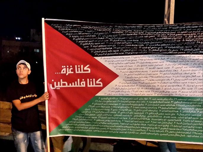 فتى يرفع علم فلسطين وطبع عليه اسماء شهداء العدوان على غزة