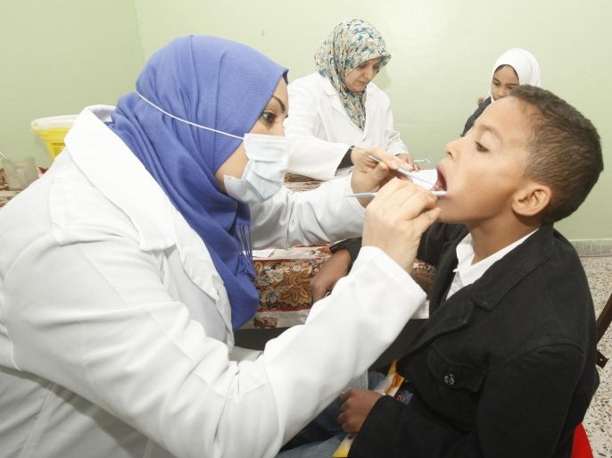 A dentist examines a student's teeth during a campaign to promote oral hygiene at a school in Janzour area, about 17 km (11 miles) west of the capital Tripoli December 11, 2012. Dentists from the Yarmouk Club charity clinic, in collaboration with the School Health Department of the Ministry of Education, perform free dental checks for students and provide each with a toothbrush and a tube of toothpaste as part of the campaign, according to a member of the clinic.