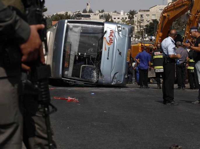 Israeli policemen stand next to an overturned bus at the scene of a suspected attack in Jerusalem August 4, 2014. A Palestinian used his heavy construction vehicle to run down and kill an Israeli and overturn the bus on a main Jerusalem street on Monday in attacks that ended when policemen shot him dead, police said. REUTERS/Siegfried Modola (JERUSALEM - Tags: POLITICS CIVIL UNREST TPX IMAGES OF THE DAY)