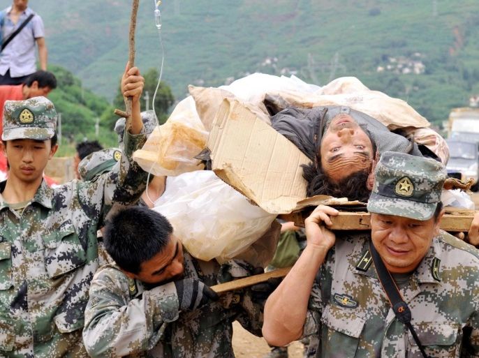 Rescuers carry an injured man during a rescue operation following Sunday's earthquake in Ludian county of Zhaotong city in southwest China's Yunnan Province, Monday, Aug. 4, 2014. Rescuers dug through shattered homes Monday looking for survivors of a strong earthquake in southern China's Yunnan province that killed hundreds and injured more than a thousand people. (AP Photo/Kyodo News) JAPAN OUT