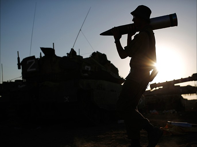 An Israeli soldier carries a tank shell in a staging area near the border with the Gaza Strip August 7, 2014. Mediators worked against the clock on Thursday to extend a Gaza truce between Israel and the Palestinians as the three-day ceasefire went into its final 24 hours. Israel has said it is ready to agree to an extension as Egyptian mediators pursued talks with Israelis and Palestinians on an enduring end to a war that devastated the Hamas-ruled enclave, while Palestinians want an Israeli-Egyptian blockade of Gaza to be lifted and prisoners held by Israel to be freed. Gaza officials say the war has killed 1,874 Palestinians, most of them civilians. Israel says 64 of its soldiers and three civilians have been killed since fighting began on July 8, after a surge in Palestinian rocket salvoes into Israel REUTERS/ Amir Cohen (ISRAEL - Tags: POLITICS CIVIL UNREST MILITARY TPX IMAGES OF THE DAY)