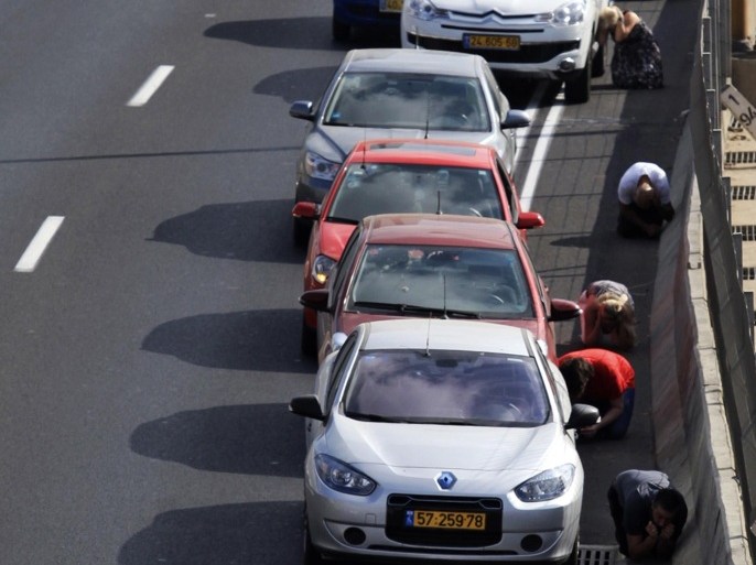 Drivers take cover beside their cars on a highway as an air raid siren, warning of incoming rockets, sounds in Tel Aviv July 9, 2014. Israeli air strikes shook Gaza every few minutes on Wednesday, and militants kept up rocket fire at Israel's heartland in intensifying warfare that Palestinian officials said has killed at least 47 people in the Hamas-dominated enclave. REUTERS/Stringer (ISRAEL - Tags: POLITICS CIVIL UNREST)