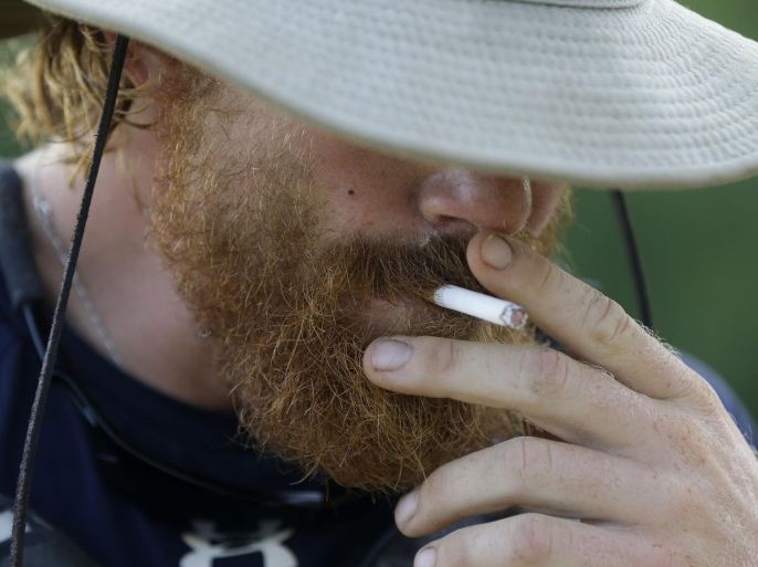 Joshua Ploetz, smokes a cigarette after setting up camp, while canoeing in the Mississippi River in Donaldsonville, La., Wednesday, July 23, 2014. The trip to the mouth of the river at the Gulf of Mexico would take 69 days, about 50 of them spent paddling. But Ploetz said he needed every inch of the more than 2,500-mile river to paddle away the demons of the war, or at least calm them a bit. (AP Photo/Gerald Herbert)