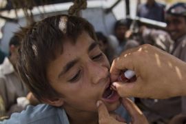 In this photo taken on Friday, June 27, 2014, a Pakistani volunteer gives polio vaccine to a displaced tribal boy in Bannu, Pakistan. The rugged Pakistani region of North Waziristan emerged as a hotbed of polio infections after Taliban militants in the isolated area banned immunizations. Now the Pakistani government's offensive against the militants has sent a half-million refugees fleeing the territory, creating both perfect conditions for the disease to spread and a golden opportunity to immunize many thousands of people. (AP Photo/B.K. Bangash)