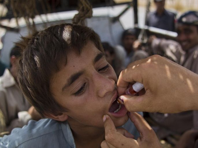 In this photo taken on Friday, June 27, 2014, a Pakistani volunteer gives polio vaccine to a displaced tribal boy in Bannu, Pakistan. The rugged Pakistani region of North Waziristan emerged as a hotbed of polio infections after Taliban militants in the isolated area banned immunizations. Now the Pakistani government's offensive against the militants has sent a half-million refugees fleeing the territory, creating both perfect conditions for the disease to spread and a golden opportunity to immunize many thousands of people. (AP Photo/B.K. Bangash)