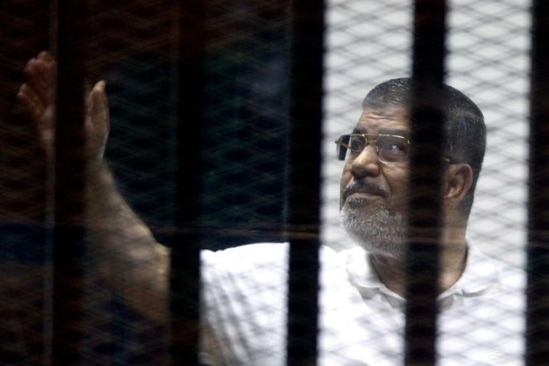 Ousted Egyptian president Mohamed Morsi stands behind dock bars during a trial session, in Cairo, Egypt, 13 July 2014. Ousted president Mohamed Morsi and some 130 defendants from the Muslim Brotherhood face a trial on charges of allegedly escaping from prison back in 2011 during the early days of the uprising.