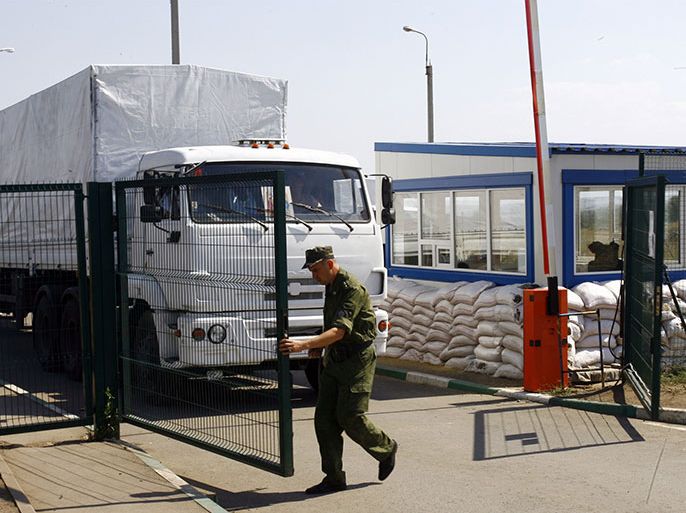 A man, opens the gate to let lorries, part of a Russian humanitarian convoy, cross the Ukrainian border at the Izvarino custom control checkpoint, on August 22, 2014. The Red Cross said its representatives were not escorting a Russian aid convoy that entered war-torn eastern Ukraine as they had not received "sufficient security guarantees." AFP PHOTO/SERGEY VENYAVSKY