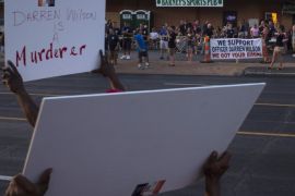 Demonstrators protesting the killing of unarmed teen Michael Brown hold placards towards Barney's Sports Pub, where supporters of officer Darren Wilson gathered in St. Louis, Missouri August 23, 2014. No arrests were recorded overnight, marking three consecutive relatively calm nights for the St. Louis suburb following daily unrest since Michael Brown, 18, was shot by Ferguson officer Darren Wilson on Aug. 9. In St. Louis, dozens of supporters of the officer gathered at Barney's Sports Pub to raise money for Wilson's family. REUTERS/Adrees Latif (UNITED STATES - Tags: CRIME LAW CIVIL UNREST)