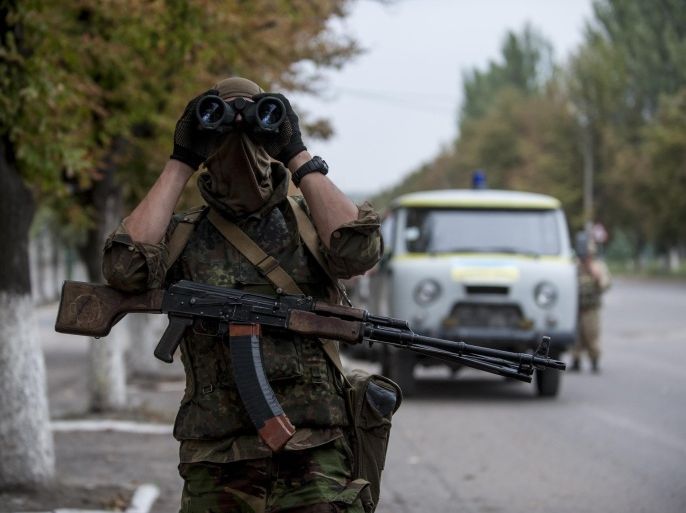 A Ukrainian government soldier from battalion "Donbass" looks through a binocular at a checkpoint next to their positions in village Mariinka near Donetsk, eastern Ukraine, Monday, Aug. 11, 2014. The Red Cross will lead an international humanitarian aid operation into Ukraine’s conflict-stricken province of Luhansk with assistance from Russia, the European Union and the United States, Ukraine said Monday.(AP Photo/Evgeniy Maloletka)