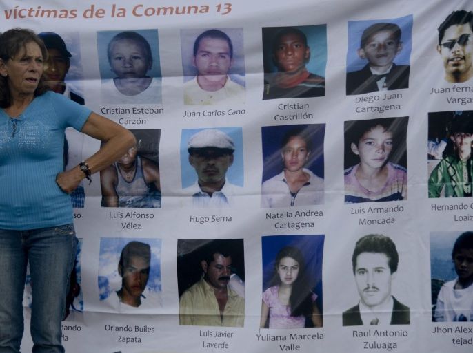 A relative of a missing person stands next to pictures of missing people at 'La Escombrera', a dumping ground for construction materials, at the Commune 13 neighbourhood, during a vigil against enforced disappearances in Medellin, Antioquia department, Colombia, on June 7, 2014. In 2002, Medellin was rocked by violence after the government's decision to recapture a sector of the city disputed by right-wing paramilitaries and militias. According to relatives of the victims, in the operation ordered on October 16, 2002 by President Alvaro Uribe, dozens of people were killed, more than 100 people were injured, 98 people went missing, and more than 200 families were displaced. AFP PHOTO/Raul ARBOLEDA