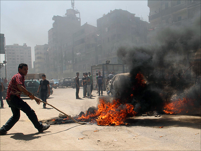 أحد المحتجين في حي المطرية بالقاهرة يسد شارعا بإطارات مطاطية مشتعلة (الفرنسية)
