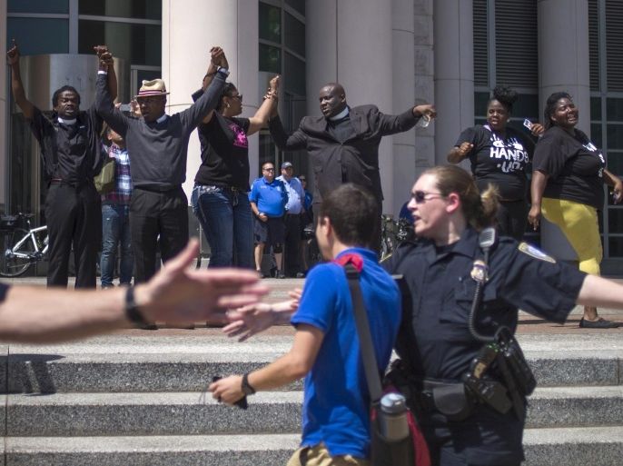 Activists raise their hands in solidarity as a policemen try to block others, who were demanding justice for the shooting death of teen Michael Brown, from advancing onto the steps to the Thomas F. Eagleton United States Courthouse in downtown St. Louis, Missouri, August 26, 2014. The slaying of the 18-year-old black youth Michael Brown by a white police officer, Darren Wilson, in the St Louis suburb of Ferguson on Aug. 9 led to days of unrest and drew global attention to race relations in the United States. REUTERS/Adrees Latif (UNITED STATES - Tags: CRIME LAW CIVIL UNREST)