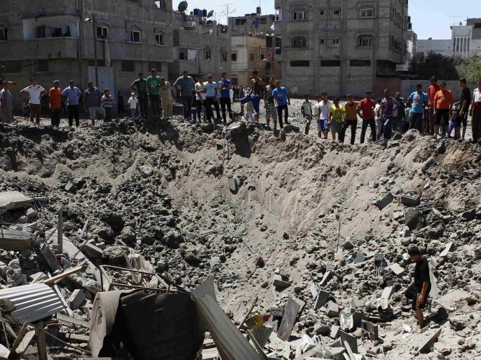 People look at a crater on the ground and damaged buildings, that witnesses said was caused by an Israeli air strike, in the Zeitoun neighbourhood in Gaza City August 8, 2014. Israel launched air strikes across the Gaza Strip on Friday in response to Palestinian rockets fired after Egyptian-mediated talks failed to extend a 72-hour truce in the month-long war. REUTERS/Siegfried Modola (GAZA - Tags: POLITICS CIVIL UNREST CONFLICT)