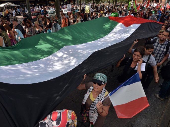 People hold a giant Palestinian flag during a demonstration against Israel's military operation in Gaza and in support of the Palestinian people in Strasbourg, eastern France, on August 9, 2014. Israeli warplanes carried out 30 air strikes over Gaza on August 9, 2014, killing five Palestinians, as militants fired six rockets into Israel, leaving international mediators scrambling to rescue ceasefire talks. AFP PHOTO /PATRICK HERTZOG