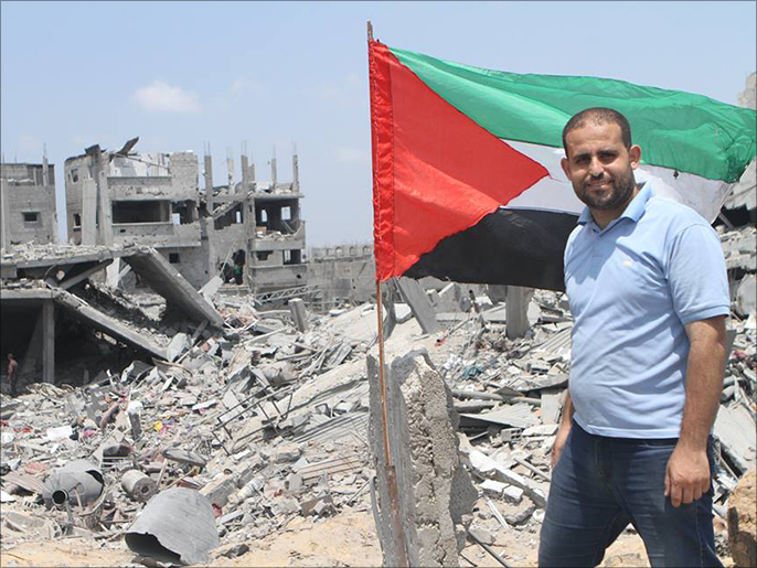 ‪المصور علاء شمالي يرفع علم فلسطين على بيته المدمر‬  (الجزيرة)