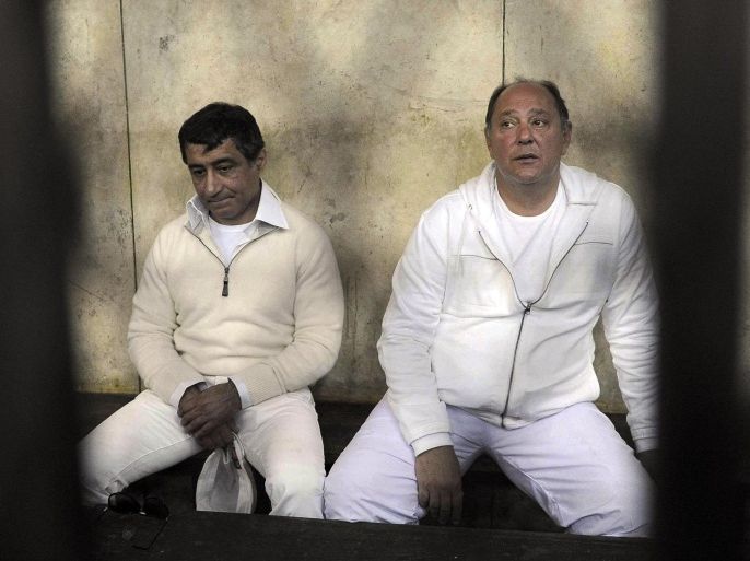 FILE - In this Thursday, Feb. 24, 2011 file photo, former Egyptian Tourism Minister Zuheir Garana, right, and steel tycoon and prominent ruling party leader Ahmed Ezz, left, wearing white prison uniforms, sit in a metal cage as they appear in the Cairo Criminal Court in Cairo, Egypt. An Egyptian court has convicted a Hosni Mubarak-era steel tycoon of profiteering and squandering public funds, and sentenced him to 37 years in prison. The court Wednesday found Ezz guilty of making illicit gains of $740 million in a number of illegal business deals involving his steel firm.