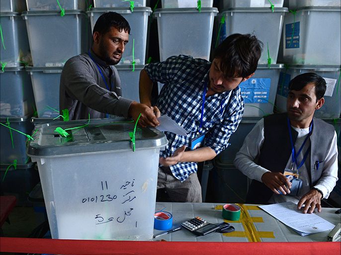 Afghan election commission workers take note while unsealing a box containing ballot papers for an audit of the presidential run-off vote in the country's general election at a counting centre in Kabul on August 3, 2014. Afghan presidential candidate Abdullah Abdullah withdrew his support from an anti-fraud audit of votes, as US-led efforts to keep the election on track descended into further uncertainty. The country's first democratic transfer of power has been engulfed in a dispute over alleged fraud, wrecking hopes that the election would be seen as a key achievement of the international military and civilian aid effort since 2001. AFP PHOTO/Wakil KOHSAR