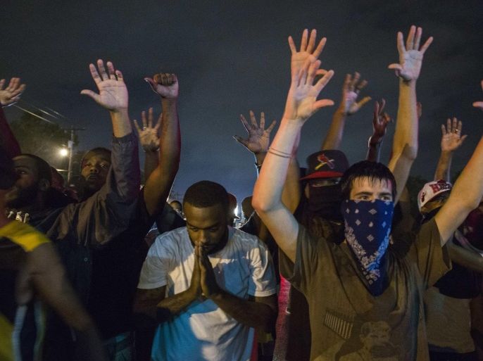 Protesters gesture as they stand in a street in defiance of a midnight curfew meant to stem ongoing demonstrations in reaction to the shooting of Michael Brown in Ferguson, Missouri August 17, 2014. The group of protesters angry at the shooting death of Brown, a black teenager, by a white police officer remained on the streets of Ferguson, Missouri, early on Sunday minutes past the declared curfew, as police began to clear the streets in a tense standoff. REUTERS/Lucas Jackson (UNITED STATES - Tags: CIVIL UNREST CRIME LAW)