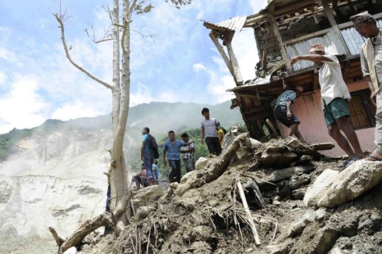 People are seen at the landslide area in Sindhupalchowk district in this handout picture dated August 2, 2014. A massive landslide triggered by heavy rains in northeast Nepal on Saturday has killed at least eight people, injured 40 and buried dozens of homes, officials said. The landslide created a mud dam blocking the Sunkoshi River near Jure in the Sindhupalchowk district, about 60 kms (37 miles) northeast of Kathmandu, heightening fears of downstream floods that could reach as far as Bihar in eastern India. REUTERS/Nepal Army/Handout via Reuters (NEPAL - Tags: DISASTER ENVIRONMENT) ATTENTION EDITORS - NO SALES. NO ARCHIVES. FOR EDITORIAL USE ONLY. NOT FOR SALE FOR MARKETING OR ADVERTISING CAMPAIGNS. THIS IMAGE HAS BEEN SUPPLIED BY A THIRD PARTY. IT IS DISTRIBUTED, EXACTLY AS RECEIVED BY REUTERS, AS A SERVICE TO CLIENTS