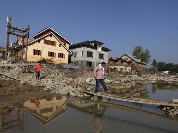 A man walks along a makeshift footbridge on a road which was damaged by floods in Srinagar September 18, 2014. Both the Indian and Pakistan sides of the disputed Himalayan territory have been hit by extensive flooding since the Jhelum river, swollen by unusually heavy rain, surged two weeks ago. Thousands have been left stranded, homeless and hungry in the city of Srinagar, most of which was submerged by the region's worst flooding in 50 years. REUTERS/Danish Ismail (INDIAN-ADMINISTERED KASHMIR - Tags: DISASTER ENVIRONMENT TPX IMAGES OF THE DAY)