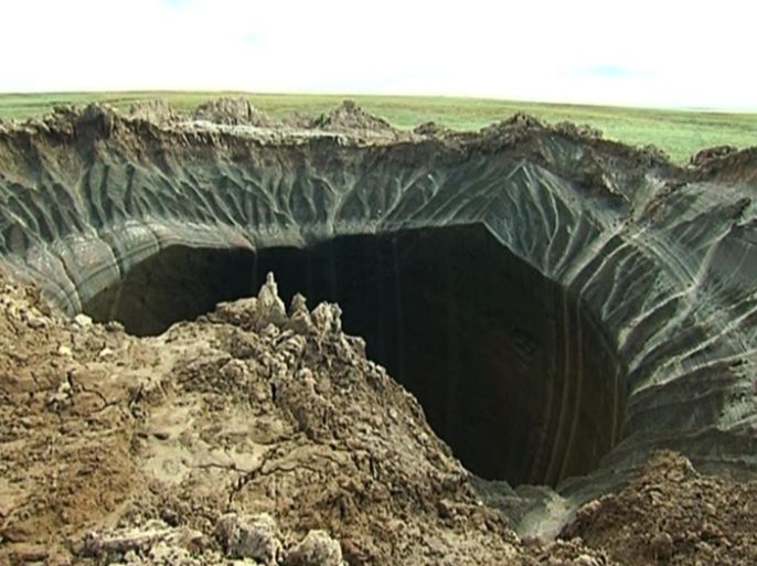 This frame grab made Wednesday, July 16, 2014, shows a crater, discovered recently in the Yamal Peninsula, in Yamalo-Nenets Autonomous Okrug, Russia. Russian scientists said Thursday July 17, 2014 that they believe a 60-meter wide crater, discovered recently in far northern Siberia, could be the result of changing temperatures in the region. Andrei Plekhanov, a senior researcher at the Scientific Research Center of the Arctic, traveled on Wednesday to the crater. Plekhanov said 80 percent of the crater appeared to be made up of ice and that there were no traces of an explosion, eliminating the possibility that a meteorite had struck the region. (AP Photo/Associated Press Television)
