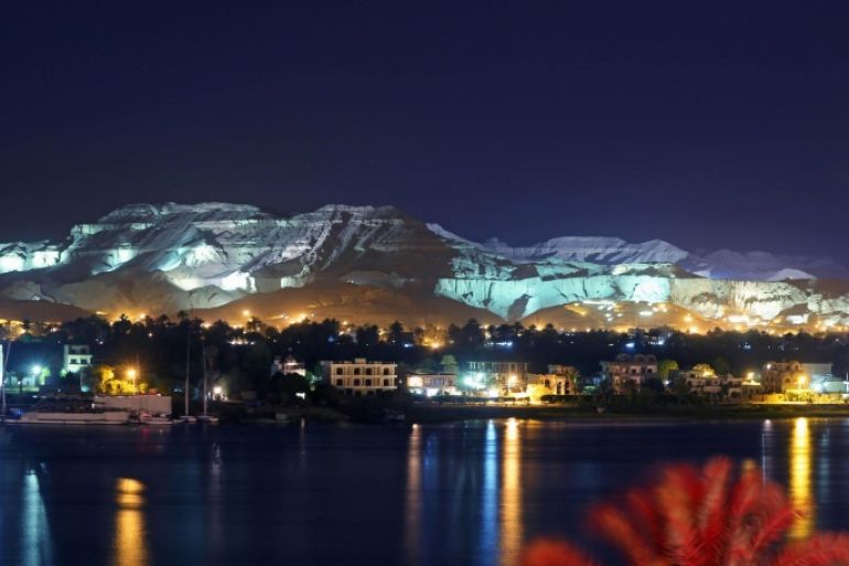 This Wednesday, April, 30, 2014 photo shows mountains illuminated by colorful lights on the west bank of the Nile River in Luxor, Egypt. on the east bank of the Nile River in Luxor, Egypt. Egyptian tourism officials, who Wednesday unveiled a replica of the tomb of King Tutankhamun in the desert valley where many of its ancient pharaohs were buried, are hoping the exhibit will help revive a tourism industry that has been heavily battered by the country's unrest since the 2011 uprising that toppled autocrat Hosni Mubarak. (AP Photo/Khalil Hamra)