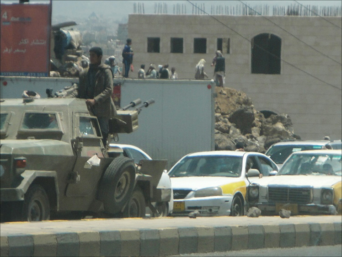 مسلحون حوثيون فوق عربة مدرعة نهبوها من معسكر للجيش اليمني بصنعاء (الجزيرة)