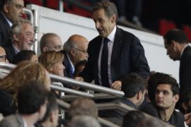 Former French President Nicolas Sarkozy (C) arrives in the tribunes prior to the French L1 football match Paris Saint-Germain (PSG) vs Lyon (OL) on September 21, 2014 at the Parc des Princes stadium in Paris. AFP PHOTO / KENZO TRIBOUILLARD